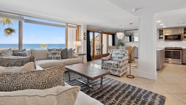 Ein geräumiges Wohnzimmer mit großem Fenster zum Meer, einer modernen Küche und einer gemütlichen Sitzecke.