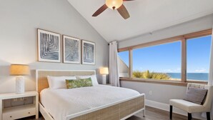 Ein Schlafzimmer mit einem großen Bett, einem Deckenventilator und Blick auf den Ozean.