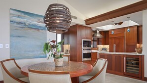 A modern kitchen with wooden cabinets, a round dining table, and a large painting on the wall.
