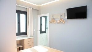 Une chambre à coucher comprenant un lit, un bureau, une chaise, une télévision et une armoire.