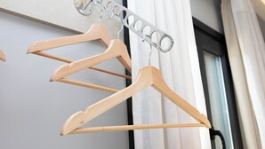 Des cintres en bois et un porte-vêtements en métal fixés au mur.