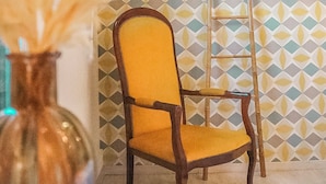 A chair with a yellow cushion and a patterned wall in the background. - Maria Grazia Hotel (Saint-Gatien-des-Bois)