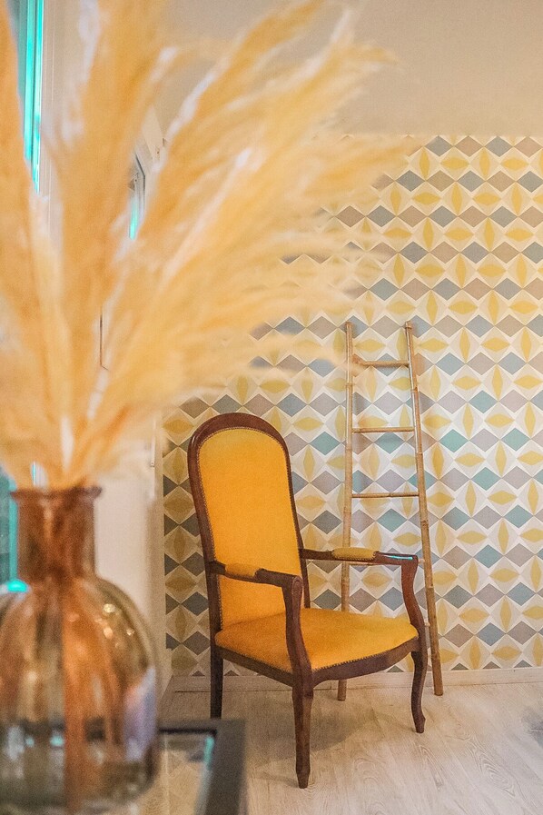 A chair with a yellow cushion and a patterned wall in the background.