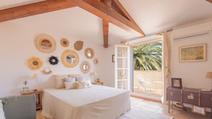 A bedroom with a bed, a nightstand, a lamp, a dresser, and a window with a view of palm trees. - House for 10 people with private pool in Sainte-Maxime. (Sainte-Maxime)