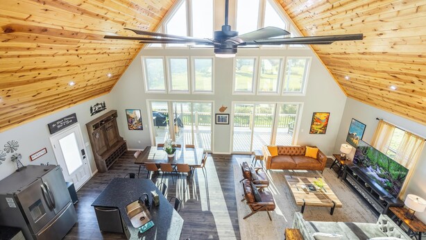 A spacious living area with a high ceiling, wooden beams, a dining area, kitchen, and a cozy seating area with a TV. - Black Diamond-New Build, Ski, Hot Tub,  Views, BBQ, EV & AC (Davis)