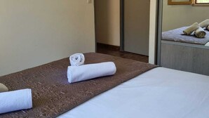 Una camera d'albergo con un letto, un tappeto di colore marrone con texture e un letto rifatto con asciugamani bianchi arrotolati.