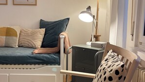 Un dormitorio con cama, una silla, un escritorio, una lámpara y un radiador.