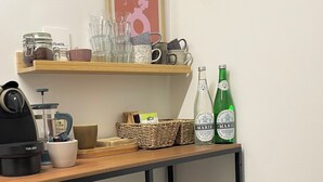 Una encimera de cocina con una cafetera, frascos, vasos y un marco con una foto.