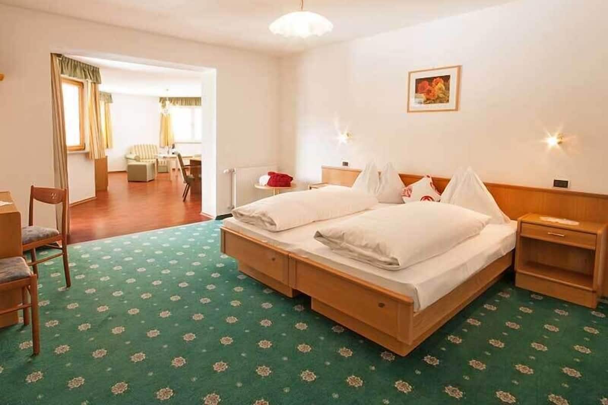 Une chambre d’hôtel avec un lit double, un bureau, une chaise, une table de chevet et une petite lampe de chevet.