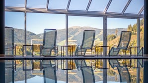 A row of chairs facing a scenic view through large windows. - Hotel Seehof (Monguelfo)