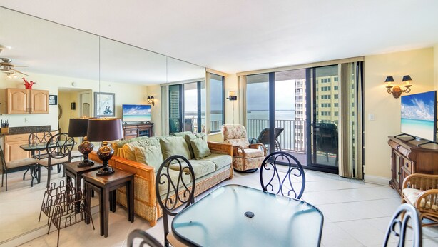 A spacious living area with a sofa, chairs, a dining table, and a balcony with a view. - Island Getaway! Lovers Key Beach Club 604, Amazing Views And Private Beach! (Fort Myers Beach)