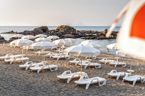Privat strand, hvit sand, solsenger og parasoller