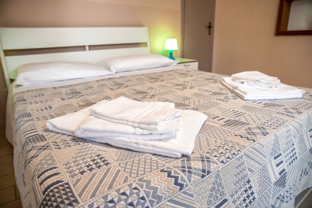 Una cama bien hecha con ropa de cama estampada y toallas dobladas.