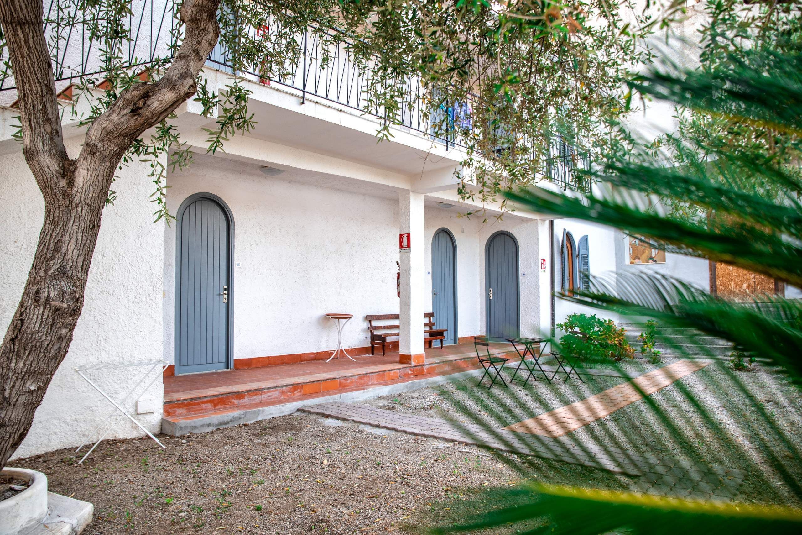 Un bâtiment à l’extérieur blanc, aux portes grises et doté d’un balcon avec une rambarde en métal.