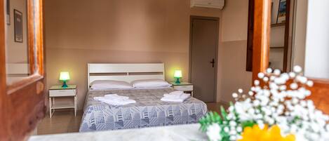 A hotel room with a bed, two bedside lamps, a wooden headboard, a nightstand, and a door.