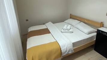 Ein Einzelbett mit hölzernem Kopfteil, einer weiß-braunen Streifendecke und zwei zusammengerollten Handtüchern auf dem Bett.
