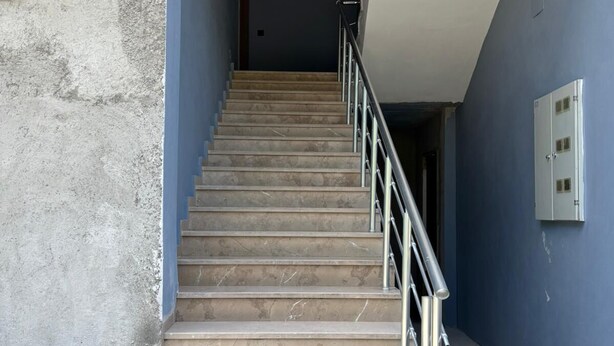 Una escalera con barandilla de metal que conduce a una habitación con pared azul y techo blanco.