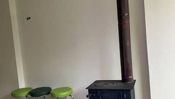 A room with a wood-burning stove, three green stools, and a white floor.