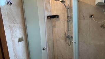 Eine begehbare Dusche mit Glastür und Handbrause.