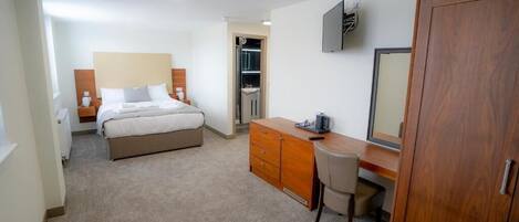 Ein Hotelzimmer mit Bett, Schreibtisch, Stuhl, Kleiderschrank, Fernseher und Bad.