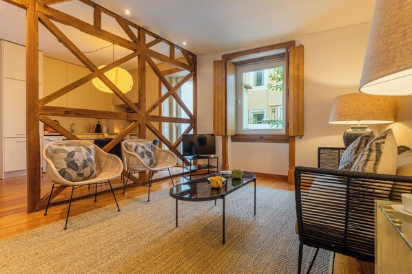 Un salón moderno con estructura de techo de madera, una mesa de centro de vidrio y dos sillones de mimbre.