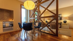 A modern kitchen with wooden beams, a dining area with a table and chairs, and a large window providing natural light. - Bairro Alto Two Bedroom Apartment (Lisbon)