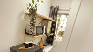 A kitchen with a microwave, a coffee maker, and a plant on a shelf. - FlexiHome (Ho Chi Minh City)