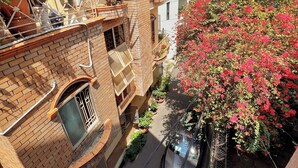 A multi-story building with a brick facade, balconies with potted plants, and a narrow street. - FlexiHome (Ho Chi Minh City)