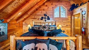 Une chambre confortable dans un chalet en rondins, avec un lit en bois, une fenêtre et une décoration sur le thème des ours.