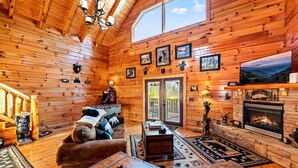 L’intérieur d’un chalet confortable, avec une cheminée, des murs en bois et une grande fenêtre.