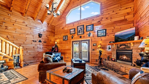 L’intérieur d’un chalet confortable, avec une cheminée, des murs en bois et une grande fenêtre.