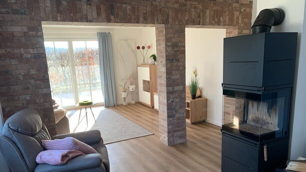 A modern living room with a fireplace, leather sofa, and a view of the outdoors. - Exceptional vacation apartment in modern style (Weiding)