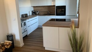 A modern kitchen with white cabinets, a wooden countertop, stainless steel appliances, and a built-in oven. - Exceptional vacation apartment in modern style (Weiding)