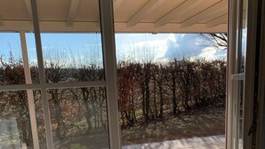 A room with a sliding glass door leading to an outdoor patio area with a tiled floor and a view of a vineyard. - Exceptional vacation apartment in modern style (Weiding)