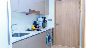 A compact kitchen with a washing machine, a coffee maker, and a sink. - Bloomfields Cozy STU in Azizi Riviera (Dubai)