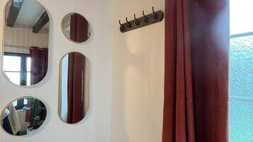 A bathroom with a wooden bench, a mirror, and a coat rack.