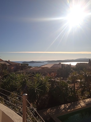 A coastal residential area with houses, a swimming pool, and a view of the sea.