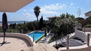 Una piscina con vistas al mar, rodeada de vegetación y un cielo despejado.