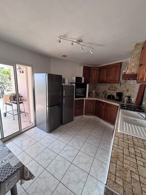 A kitchen with a refrigerator, microwave, stove, and sink.
