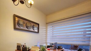 Ein Homeoffice mit einem Holztisch, zwei schwarzen Stühlen, einem Laptop und einem Topf mit Pflanze.
