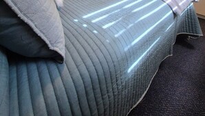 Ein Hotelzimmer mit einem Bett, einem an der Wand befestigten Fernseher und einer Tür zu einem weiteren Raum.