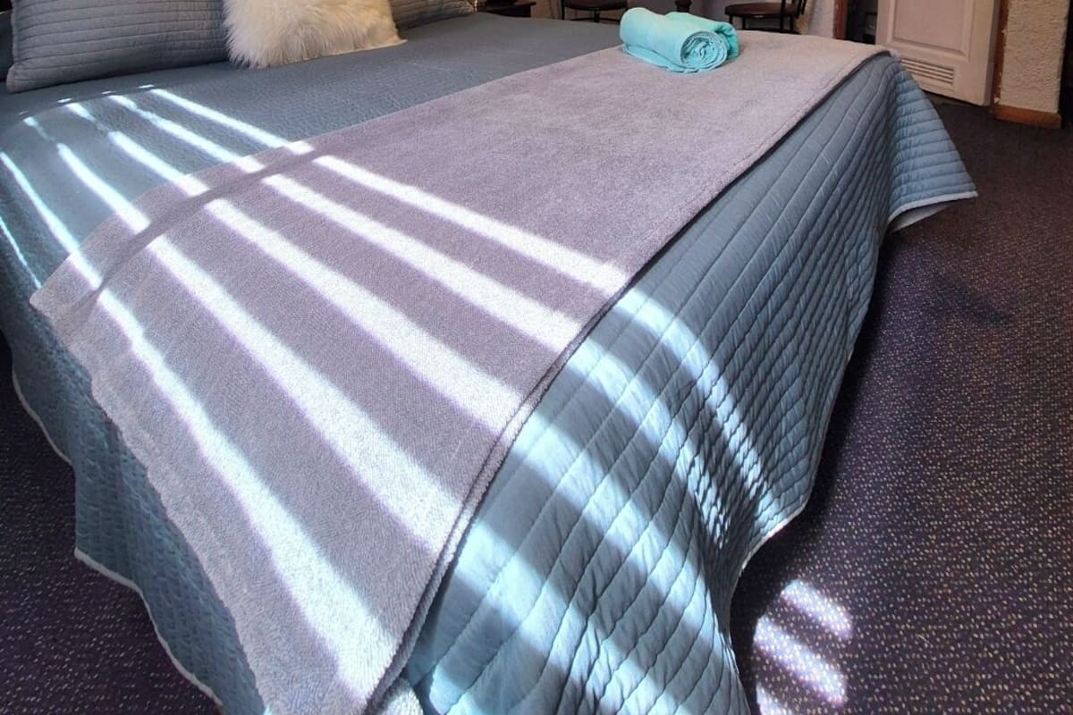 Ein Schlafzimmer mit Bett, Stuhl, Tisch und einer Tür.