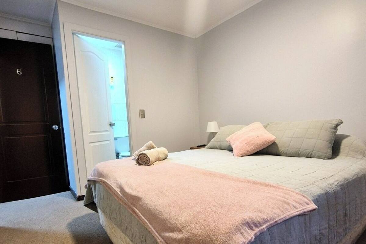 Ein Schlafzimmer mit einem Bett, einem Nachttisch und einer Tür.