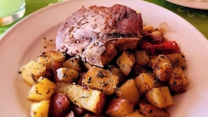 Ein Teller mit gebratenem Fleisch und gewürzten Kartoffeln.
