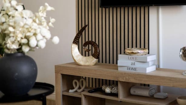 Una consola de madera con un cuerno decorativo, una pila de libros y un tazón.