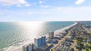 A coastal cityscape with a beachfront, high-rise buildings, and a clear sky.