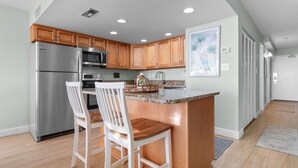 A modern kitchen with wooden cabinets, stainless steel appliances, and a granite countertop.