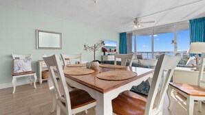 A dining area with a wooden table, white chairs, and a chandelier.