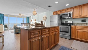 A modern kitchen with wooden cabinets, stainless steel appliances, and a large island.