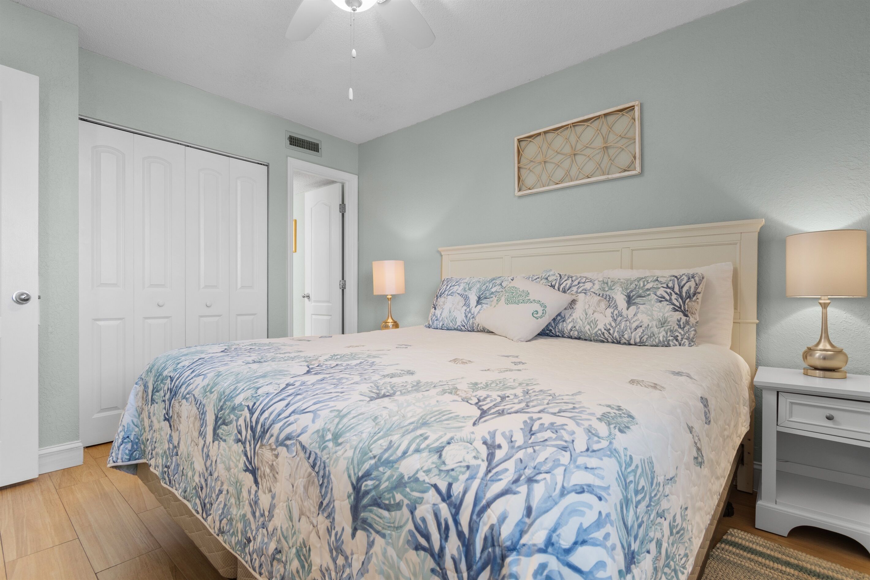 A bedroom with a bed, two bedside lamps, a nightstand, and a door.
